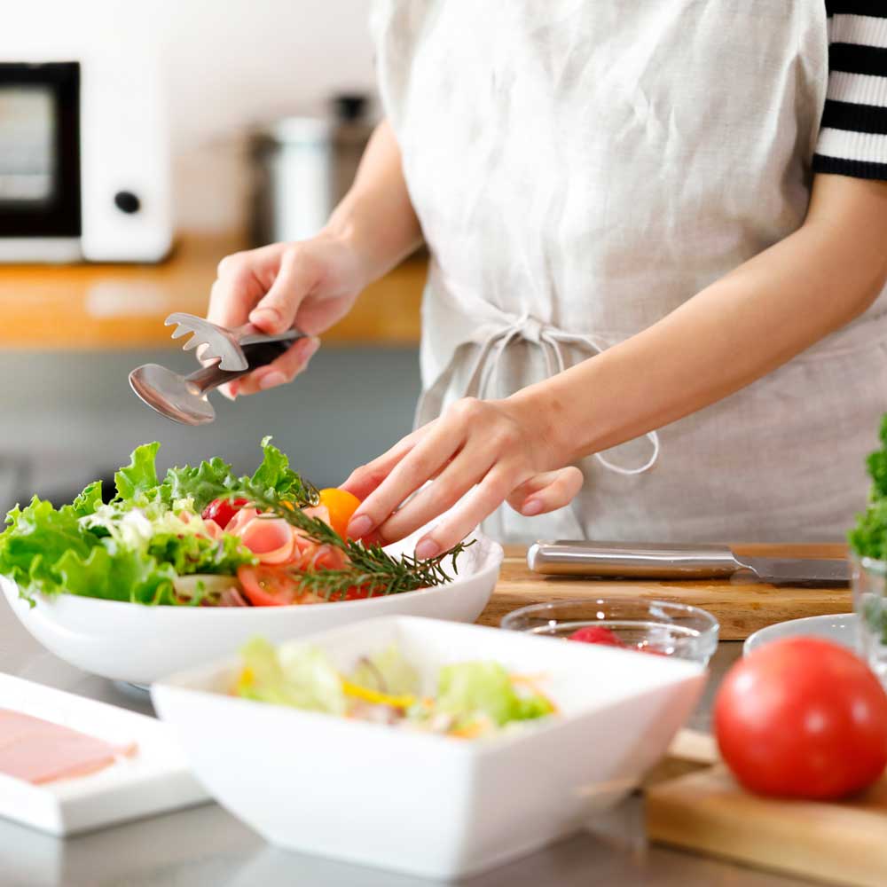 料理を盛り付ける女性の写真